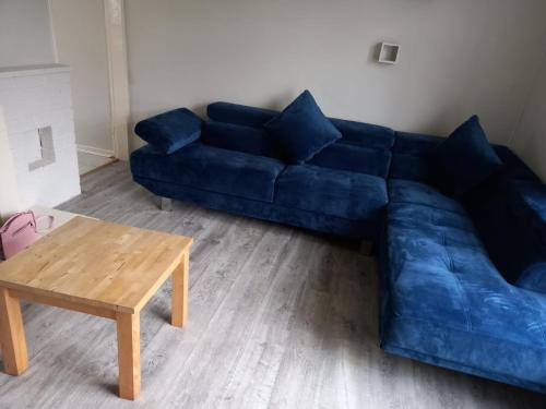 een blauwe bank in een woonkamer met een tafel bij Amazing 3 bedroom house with parking. in Nottingham