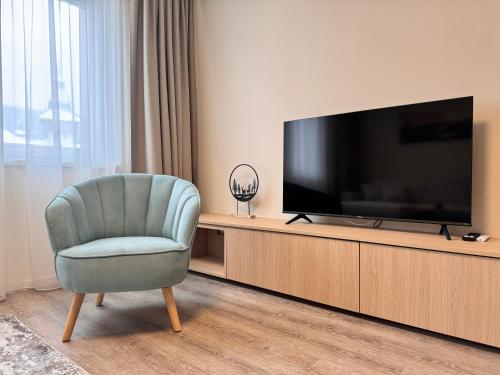 a living room with a television and a chair at Smrek Apartments in Oravská Lesná