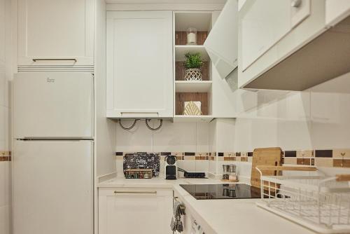 uma cozinha branca com armários brancos e um frigorífico em Little Arboli Little Apartments em Cádiz