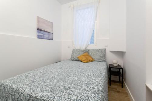 um pequeno quarto com uma cama e uma janela em Apt + patio privado Atocha Delicias Madrid Rio em Madrid