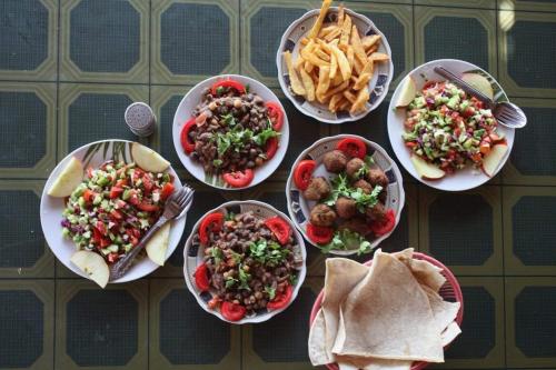 una mesa cubierta con platos de comida y patatas fritas en انتيكا كامب en Taba