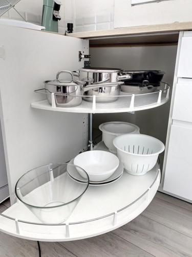 a kitchen with white shelves with bowls and pans at Mazet NiMiSa in Marseillan