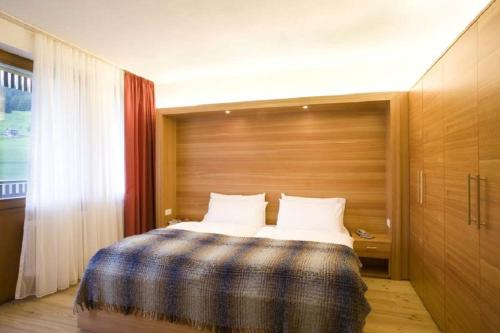 een slaapkamer met een bed met een houten muur bij Residence La Villa in La Villa