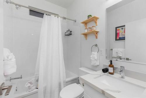 La salle de bains blanche est pourvue d'une douche et de toilettes. dans l'établissement Cozy Oasis in the heart of Capitol Hill, à Seattle