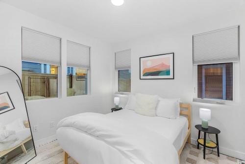 a white bedroom with a white bed and windows at Cozy Oasis in the heart of Capitol Hill in Seattle