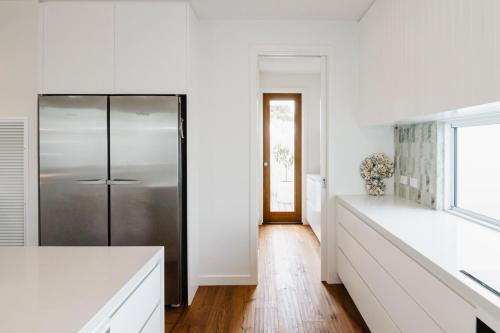 a kitchen with a stainless steel refrigerator and white walls at Beachside Mornington house in Mornington