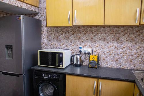 a kitchen with a microwave and a refrigerator at John's Cottage in Apenkwa