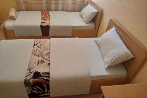 キガリにあるCentre d'Accueil Bonne Esperance Rwandaのベッド2台(白いシーツ、枕付)
