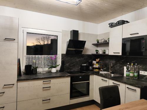 una cocina con armarios blancos y encimeras negras en Casa Tara en Döbriach