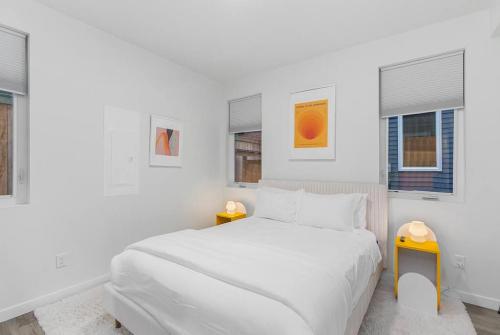 a white bedroom with a bed and two windows at Calm Urban Abode steps to Volunteer Park in Seattle