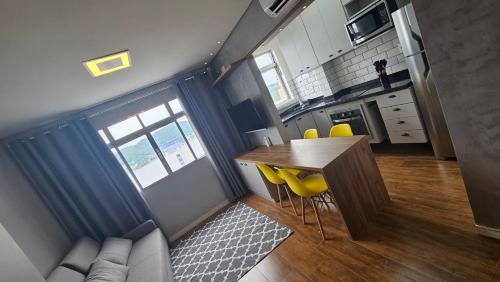 a small kitchen with a table and yellow chairs at Dias na Praia in São Vicente