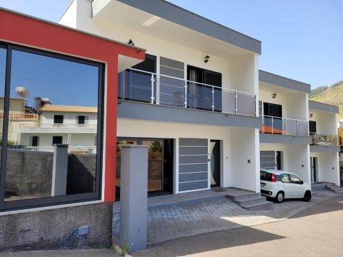 a house with a balcony and a car parked in front at Elegant Terraced Home with FREE Private Parking in Machico