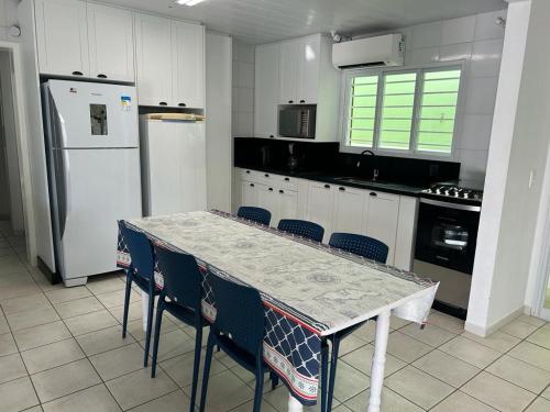 cocina con mesa, sillas y nevera en Casa incrível a Beira Mar! 3 qtos Ponta do Papagaio, en Palhoça