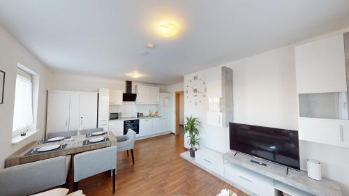 a kitchen with white cabinets and a large flat screen tv at CROWN LIVING Design Apartment - gratis Parkplatz - WLan - Küche - Self Check-in in Dornbirn