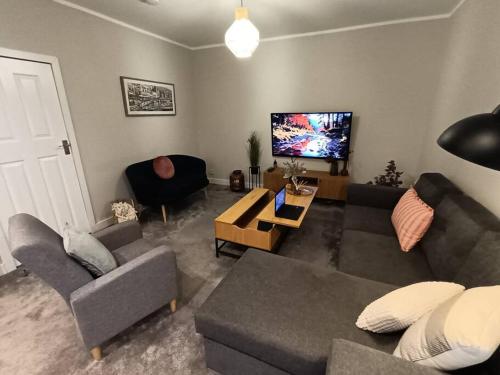 a living room with a couch and a flat screen tv at The Tansley Gardens in Darlington