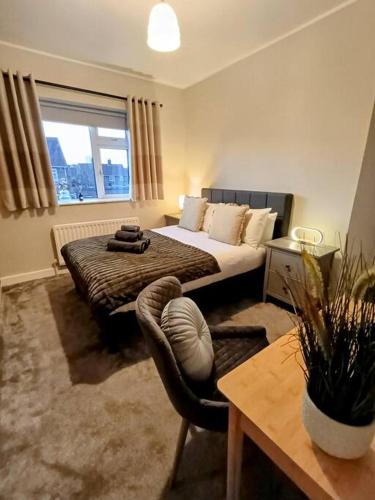 a bedroom with a bed and a chair and a window at The Tansley Gardens in Darlington