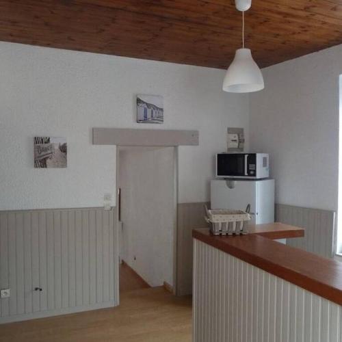 une cuisine avec un comptoir et un four micro-ondes sur le mur dans l'établissement Les Aigrettes, en plein centre, à 200m de la plage, à Saint-Vaast-la-Hougue