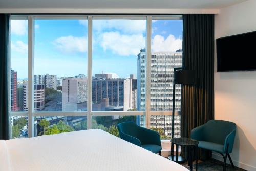 a room with a bed and two chairs and a large window at Four Points by Sheraton Auckland in Auckland