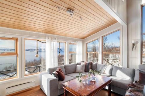 a living room with a couch and a table and windows at Hytte paradis i Kviby in Kviby