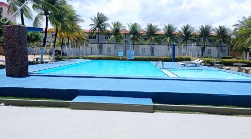 a large blue swimming pool with palm trees at Apt no Icaraí mobiliado de frente para a praia. in Caucaia