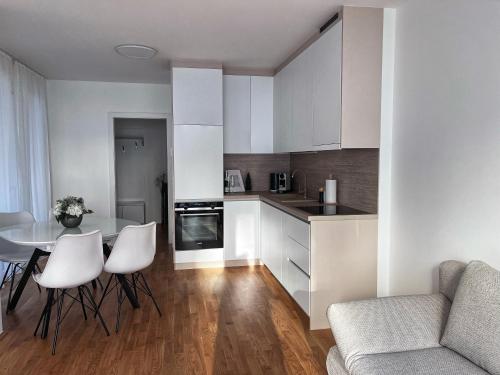 Danube22 Apartment 2 في فيينا: مطبخ مع دواليب بيضاء وطاولة وكراسي