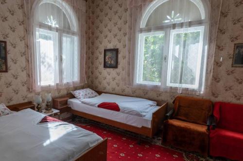 1 Schlafzimmer mit 2 Betten, einem Stuhl und 2 Fenstern in der Unterkunft Apartment Milinkovic in Kovanluk