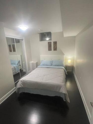 a white bedroom with a bed and a mirror at Zen Nest in Brampton