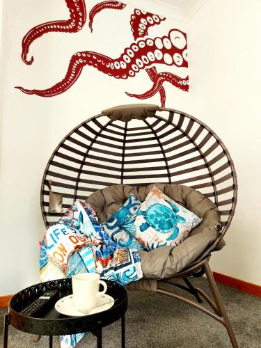 a chair in a room with a table and an octopus on the wall at The Octopus - at Largs Town Centre with Private Parking in Largs