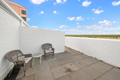un patio con 2 sillas y una mesa en una pared blanca en Sunswept 806 Condo, en Orange Beach