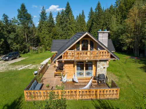 a log cabin with a porch and a deck at Oskarówka domek w górach na odludziu z jacuzzi i sauną - kominek i Netflix in Szczawa