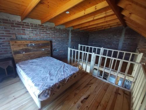 a bedroom with a bed and a brick wall at Chalet y Cabaña de montaña Esmeralda in Villa del Dique