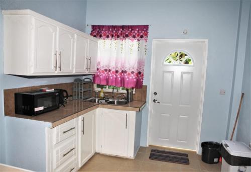a kitchen with white cabinets and a sink and a door at Paradise Apartment in Castries