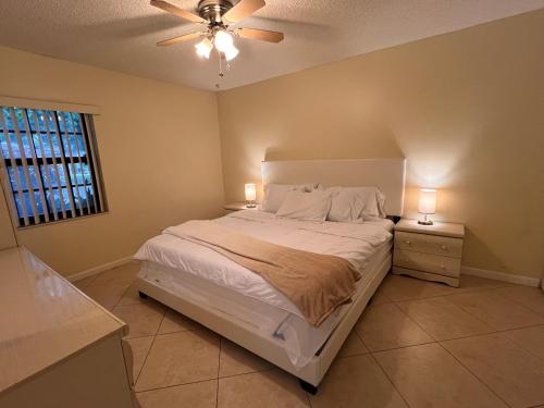 a bedroom with a bed with two night stands and a ceiling fan at Entire Single Family home 3 bed 2 bath in water front big cozy back yard view in Coconut Creek
