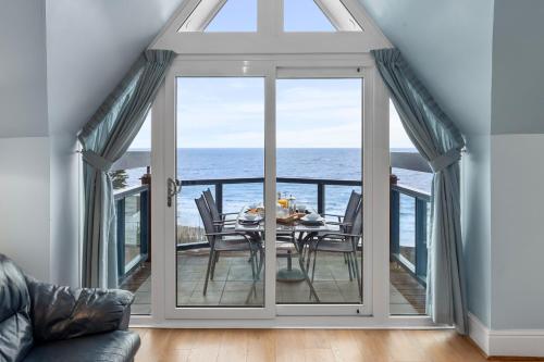 a dining room with a table and a view of the ocean at Schooner House - Panoramic Sea Views and Parking in Saundersfoot