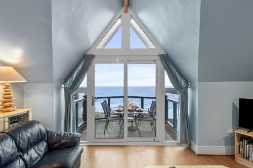 a living room with a table and a view of the ocean at Schooner House - Panoramic Sea Views and Parking in Saundersfoot