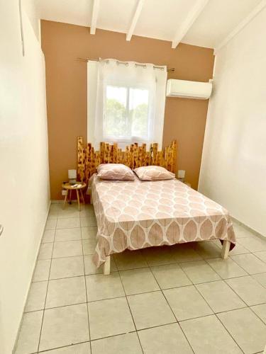 a bedroom with a bed and a window at Location Les Flamboyants in Sainte-Anne