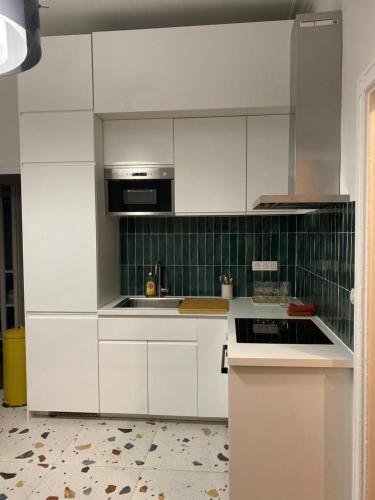 a kitchen with white cabinets and a stove top oven at Nîmes Appartement de charme Terracotta in Nîmes