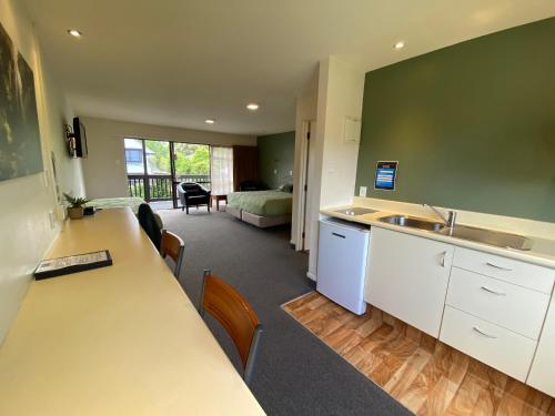 a kitchen with a sink and a room with a bed at Commodore Motel in Dunedin