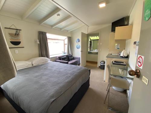 a hotel room with a bed and a kitchen at Commodore Motel in Dunedin