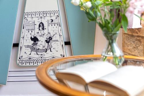 a table with a book and a vase of flowers at Domo Anghèleda - Alghero casa indipendente vicino al mare in Alghero