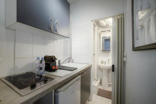 Il comprend une petite cuisine blanche avec un lavabo et des toilettes. dans l'établissement Magnifique appartement Tour Eiffel / Rue Cler, à Paris