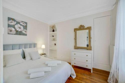 une chambre blanche avec un grand lit et un miroir dans l'établissement Magnifique appartement Tour Eiffel / Rue Cler, à Paris