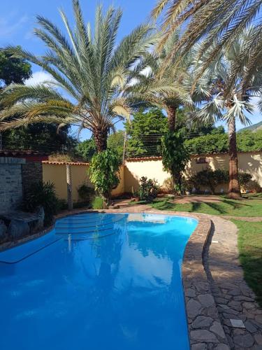 a blue swimming pool with palm trees in the background at Villa Cococaribic Isla Margarita Venezuela in Paraguachi