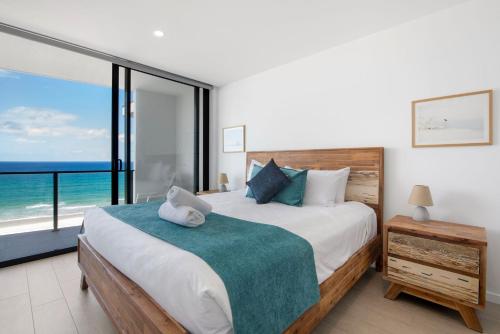 a bedroom with a bed with a view of the ocean at Ocean Views Apartment with Rooftop Pool - CoastHM in Gold Coast