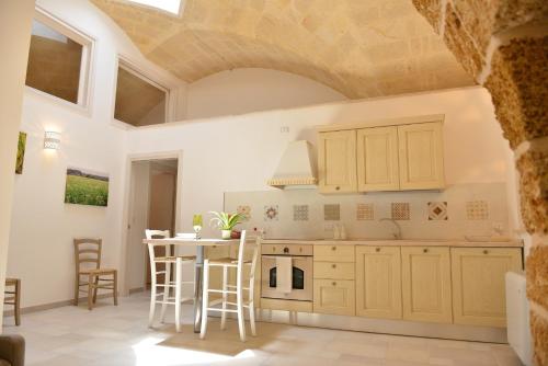 a kitchen with white cabinets and a table with chairs at Tobacco Suite in Mesagne