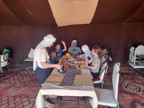 a group of people standing around a table in a tent at Casa Familia in Zagora