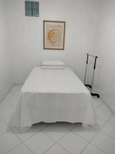 a white bed in a white room with a picture at Fantástico in Santo Amaro