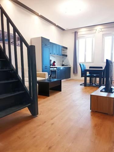ein Wohnzimmer mit einer Treppe und eine Küche in der Unterkunft Grand studio avec mezzanine in Voiron