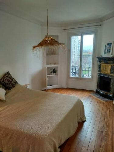 a bedroom with a large bed and a large window at Lumineux,chic, appartement Haussmannien de 50 m2 in Clichy
