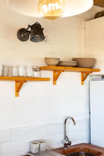 a kitchen with wooden shelves on the wall at Cabaña Agua de Mar in Punta Del Diablo